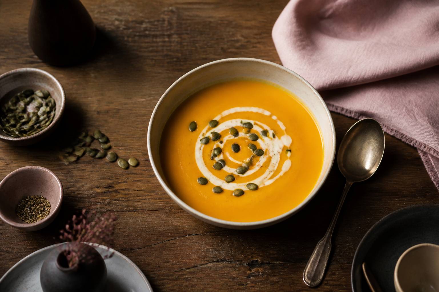 Bol de velouté orange de courge butternut avec graines et crème sur table en bois